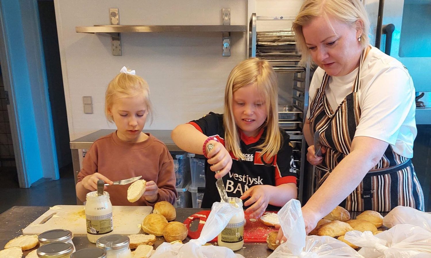 Frida og Emilie hjælper Annette med at producere frikadellesandwich til byfesten.